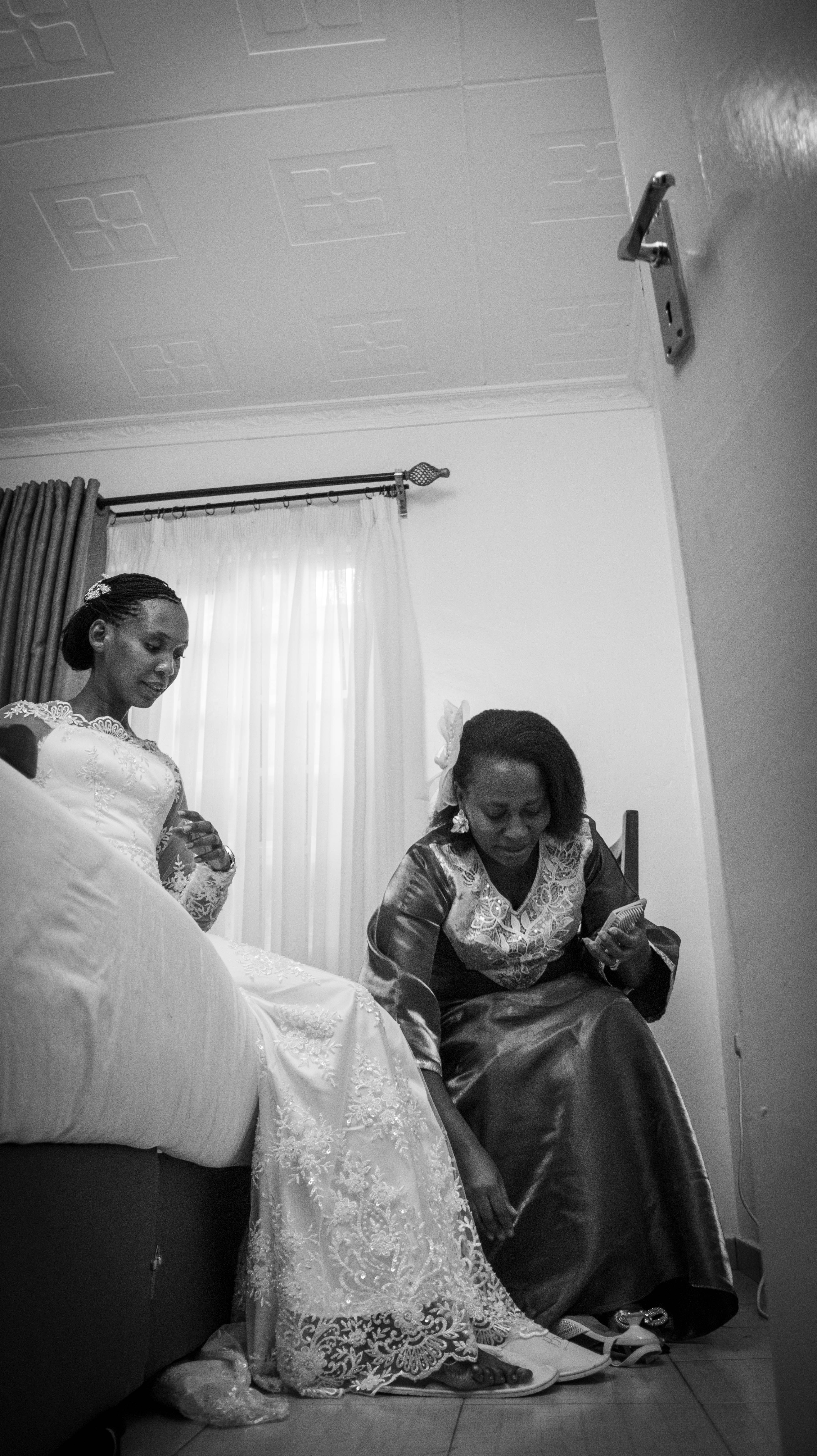 Black and white photo of the bride seated in her gown while a woman sits beside her