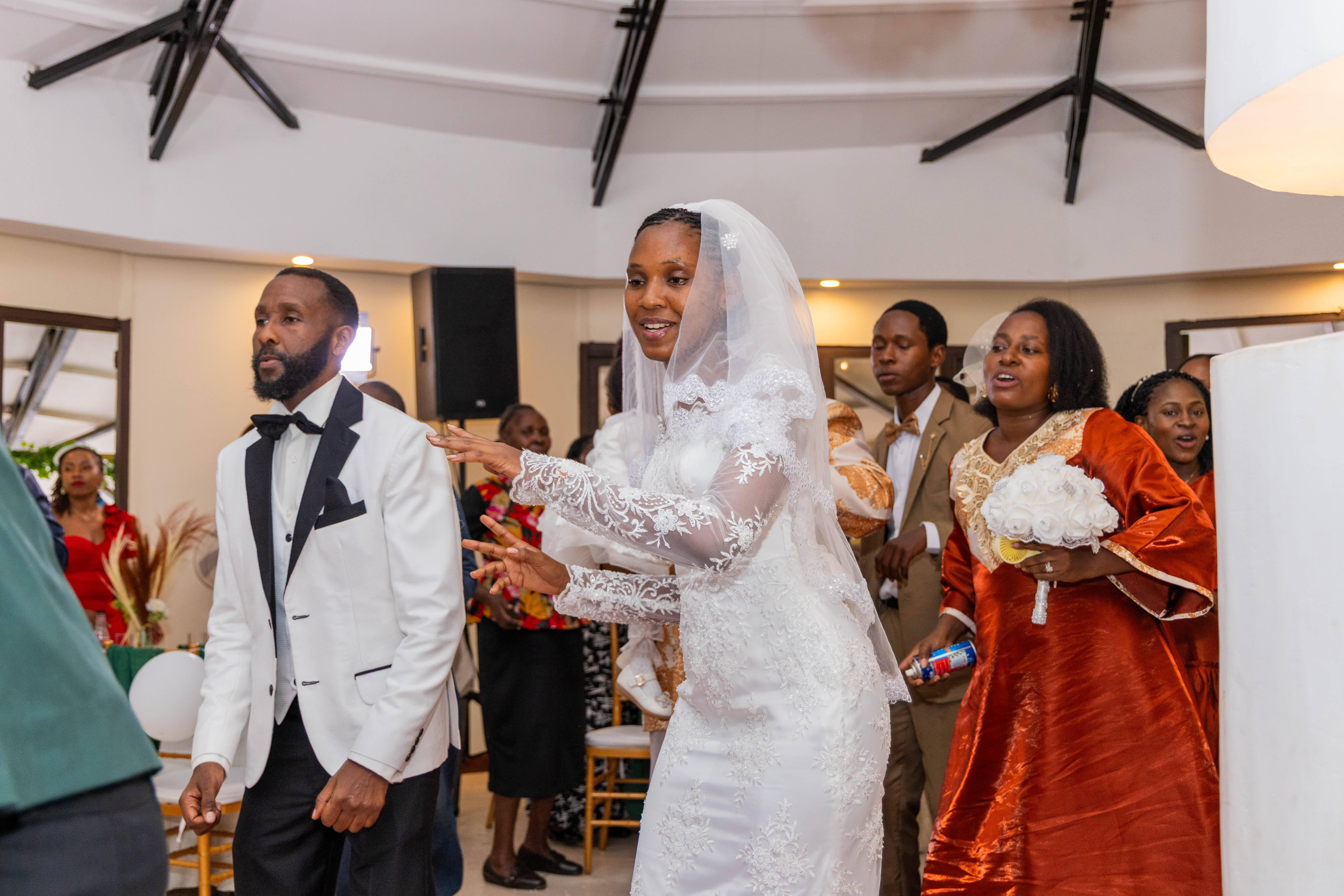The couple dances into the reception surrounded by guests in bright outfits