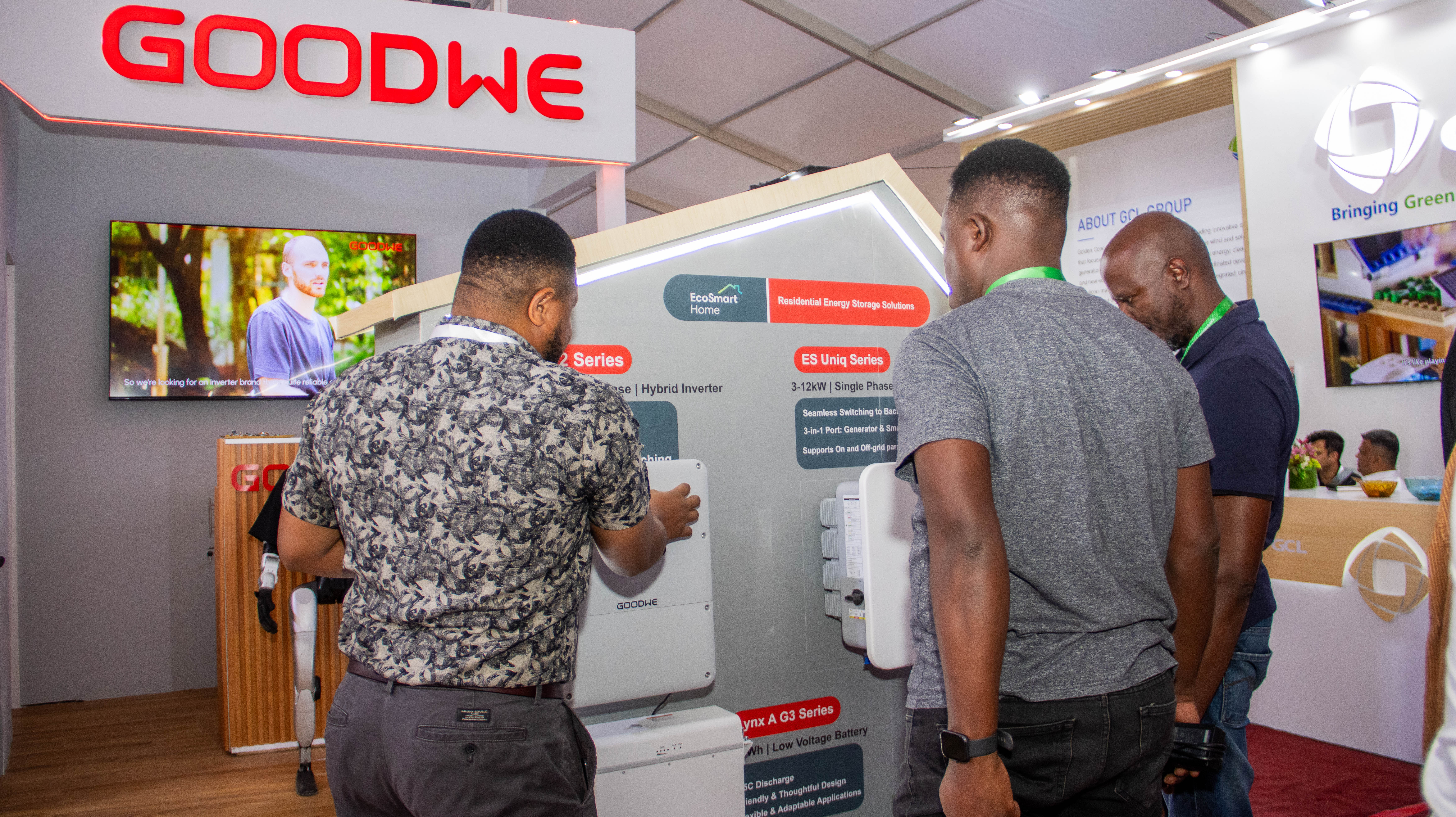 Visitors examine wall-mounted inverters at a branded exhibition booth