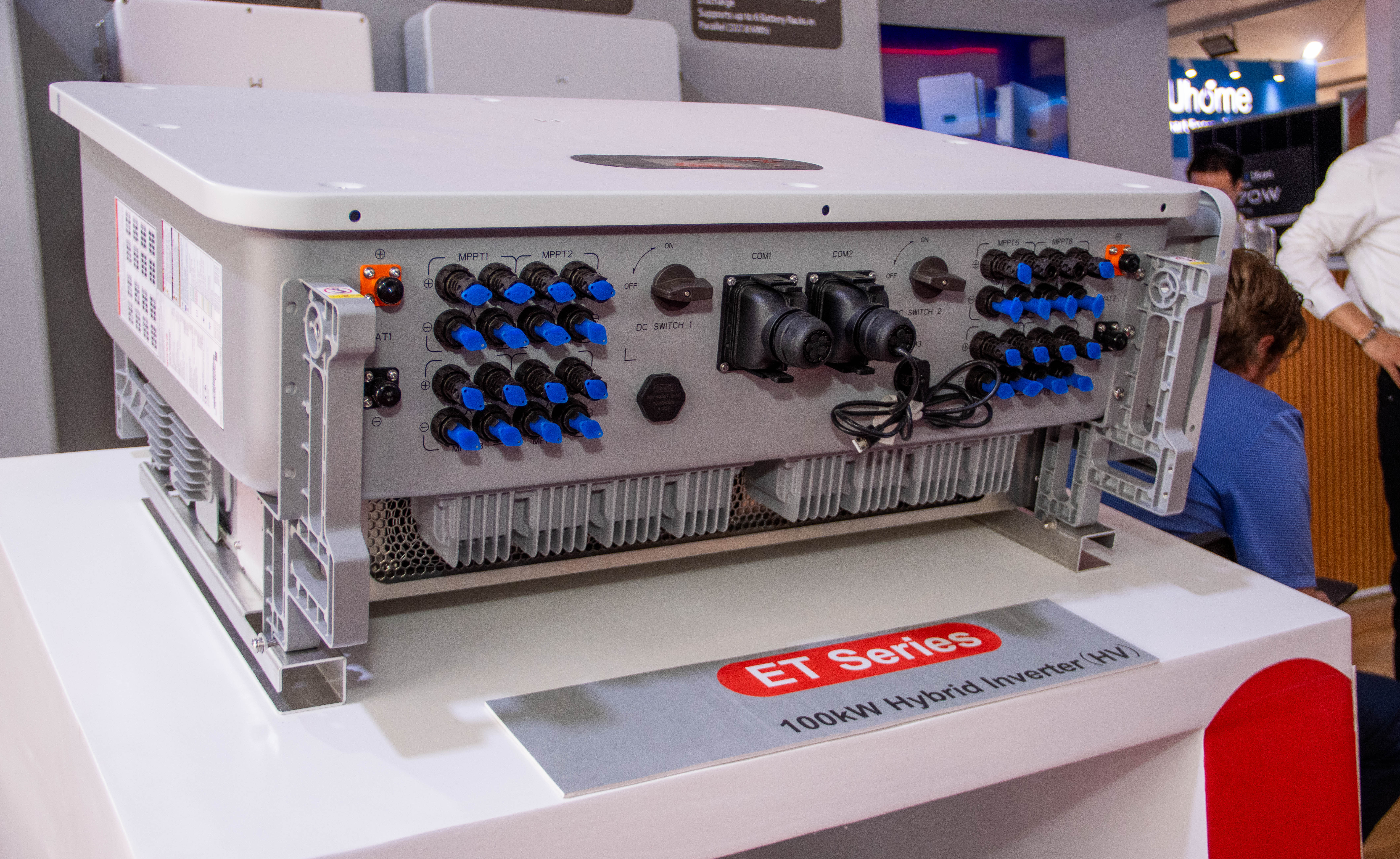 Close-up of a large grey hybrid inverter with rows of blue connectors on a display plinth