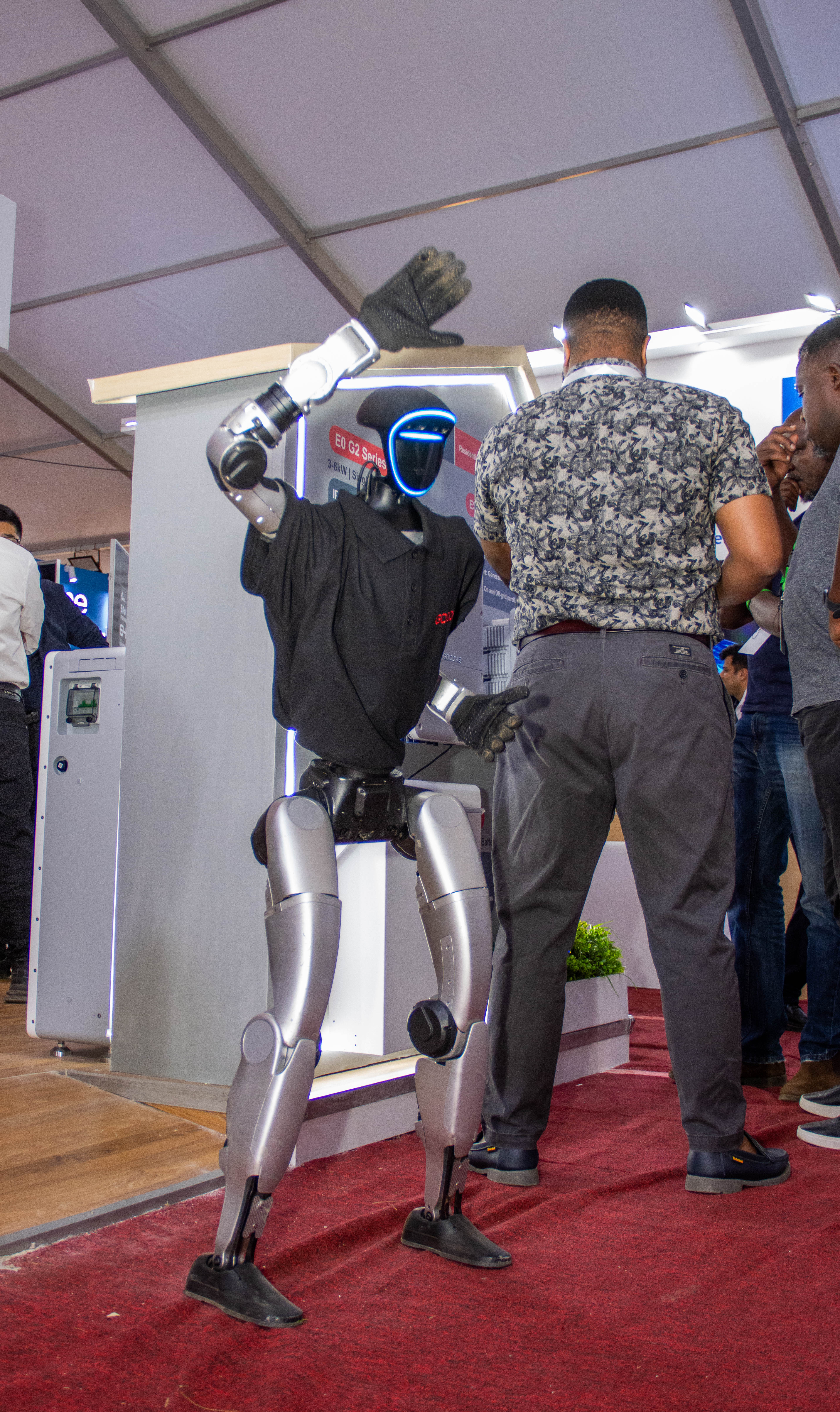 A humanoid robot strikes a pose next to a visitor at the stand