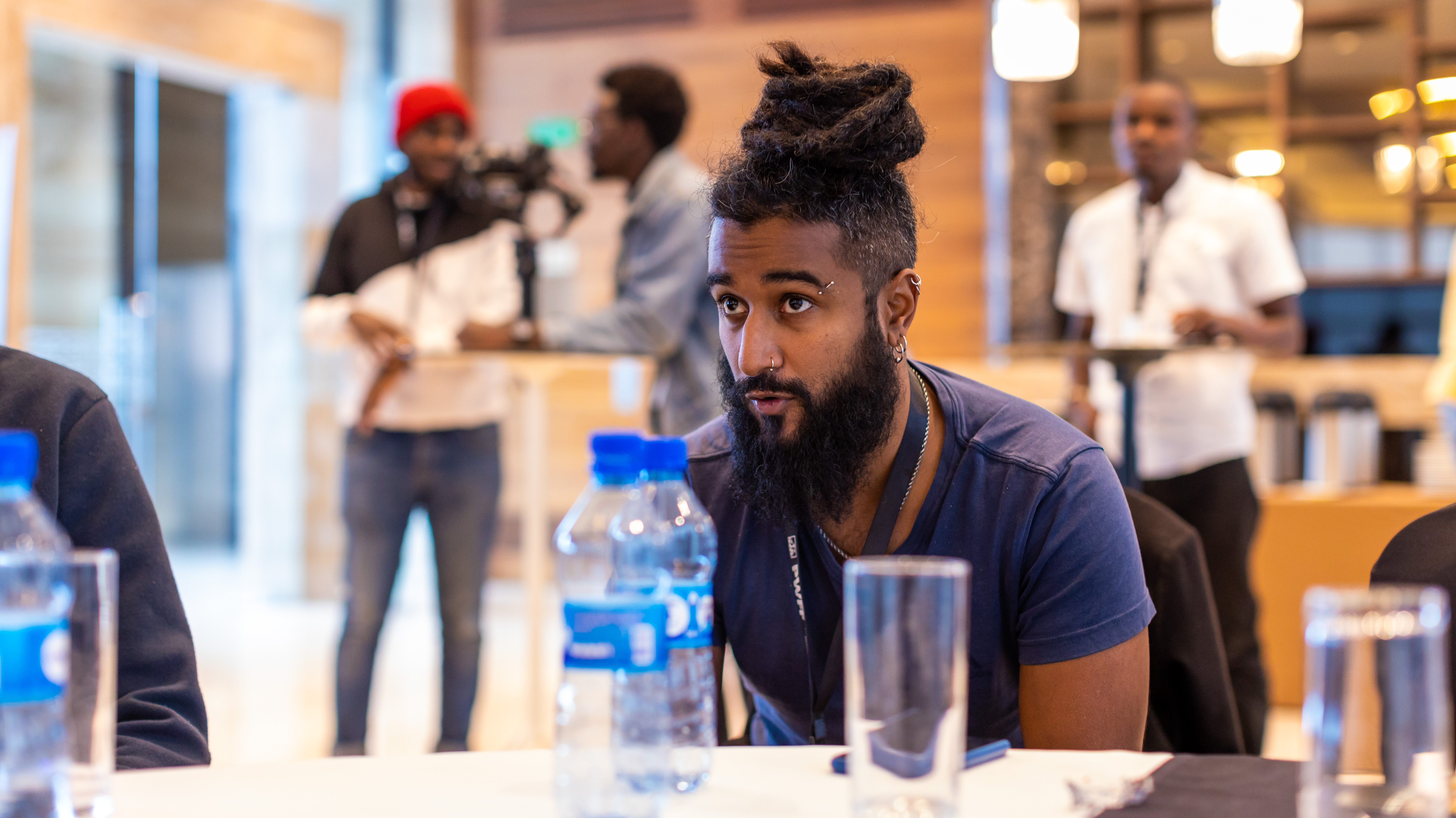 A man with locs leans forward at a table during a session