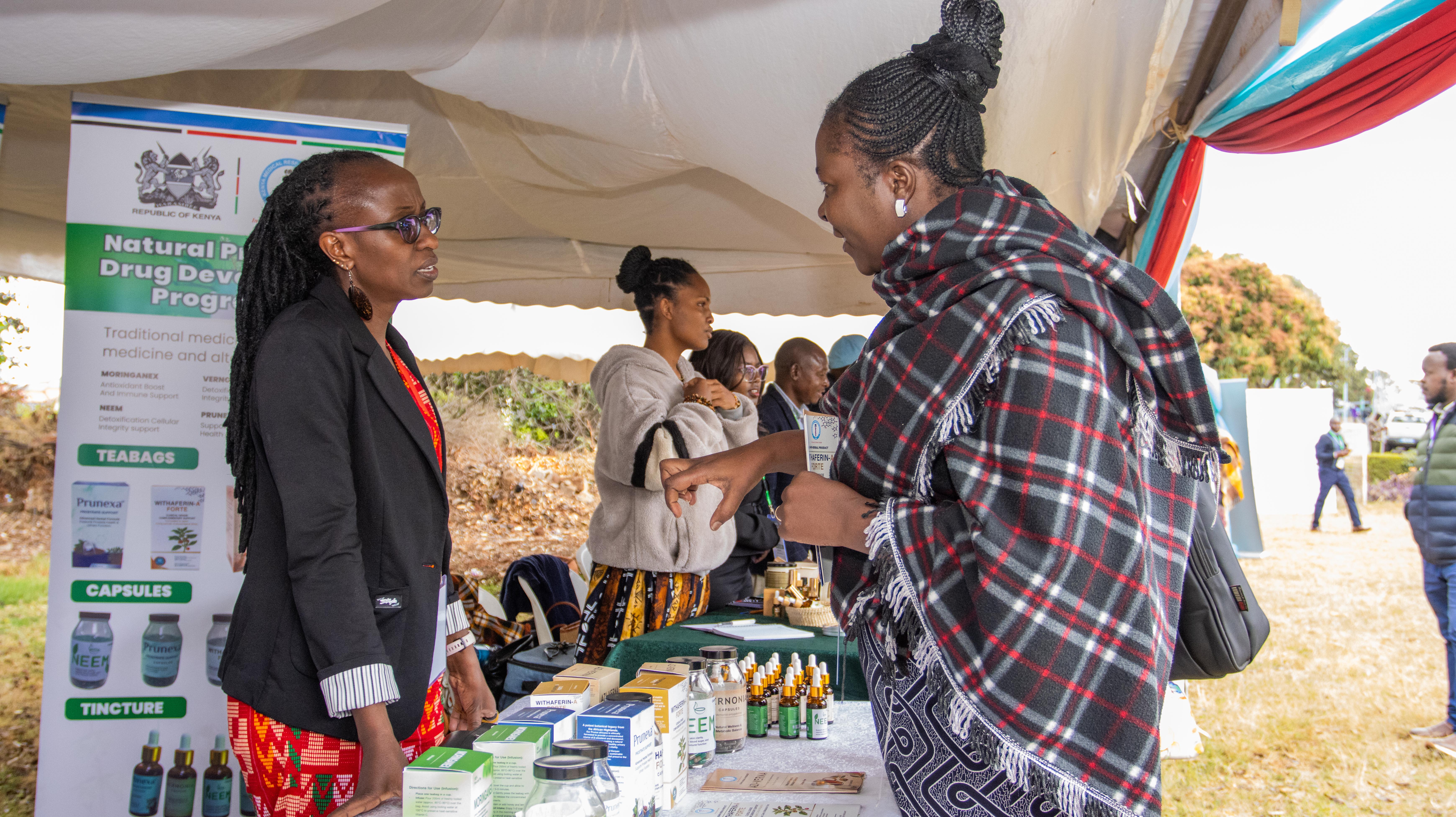Visitors talk with an exhibitor at a stall displaying natural medicine products