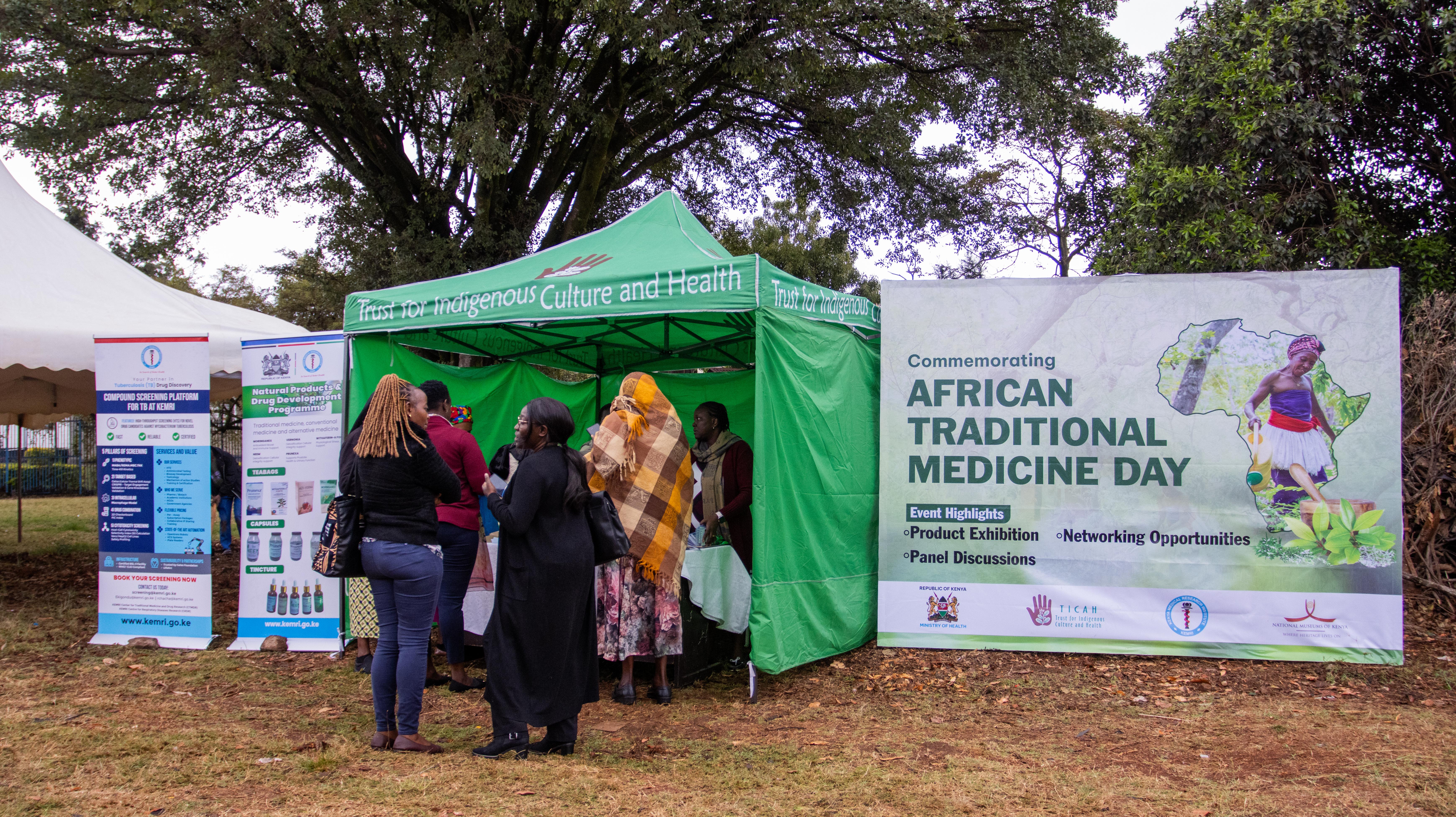 A green tent and event banners stand on a lawn as visitors gather
