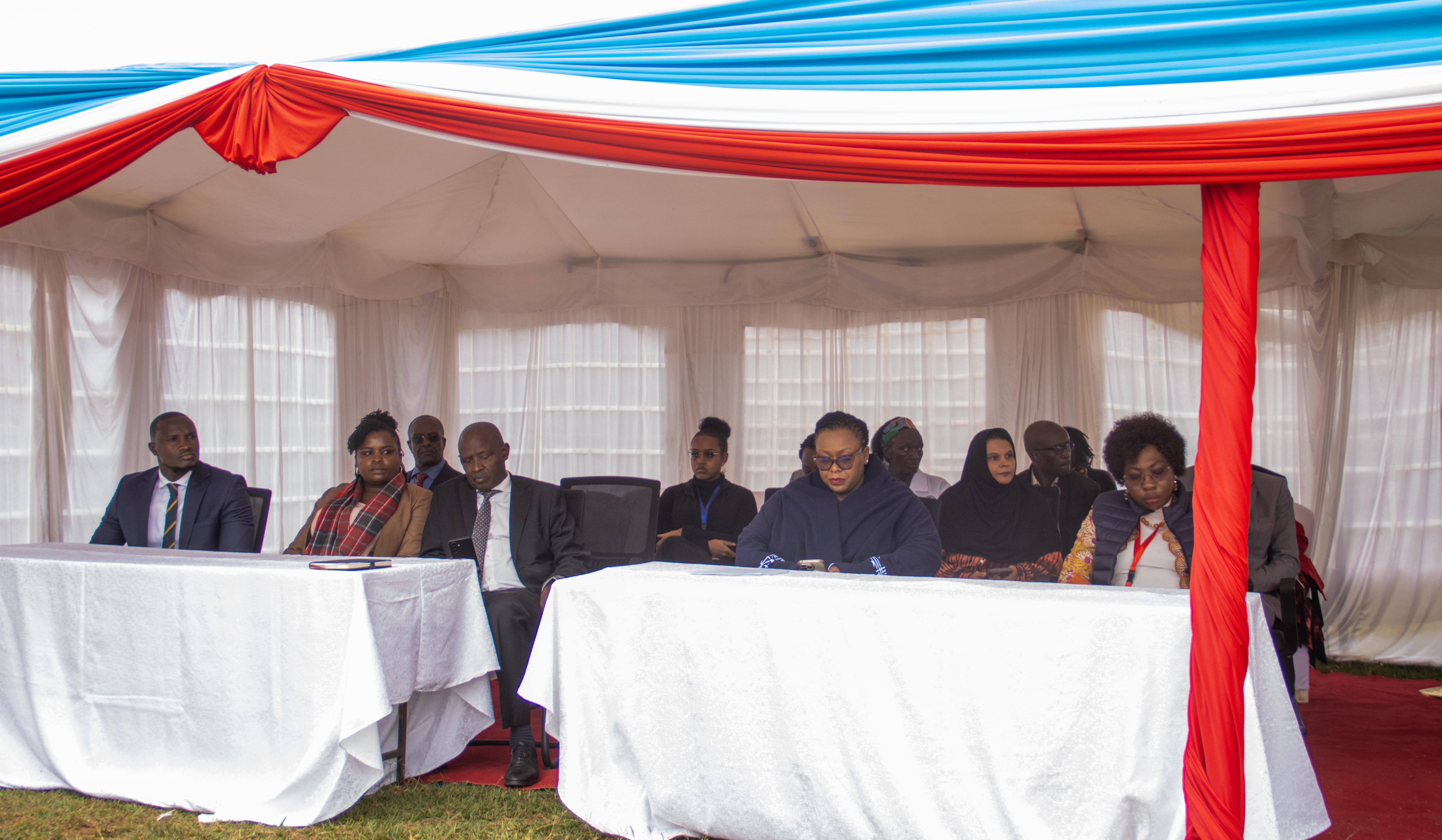 Guests seated at tables draped in white under a red and blue tent