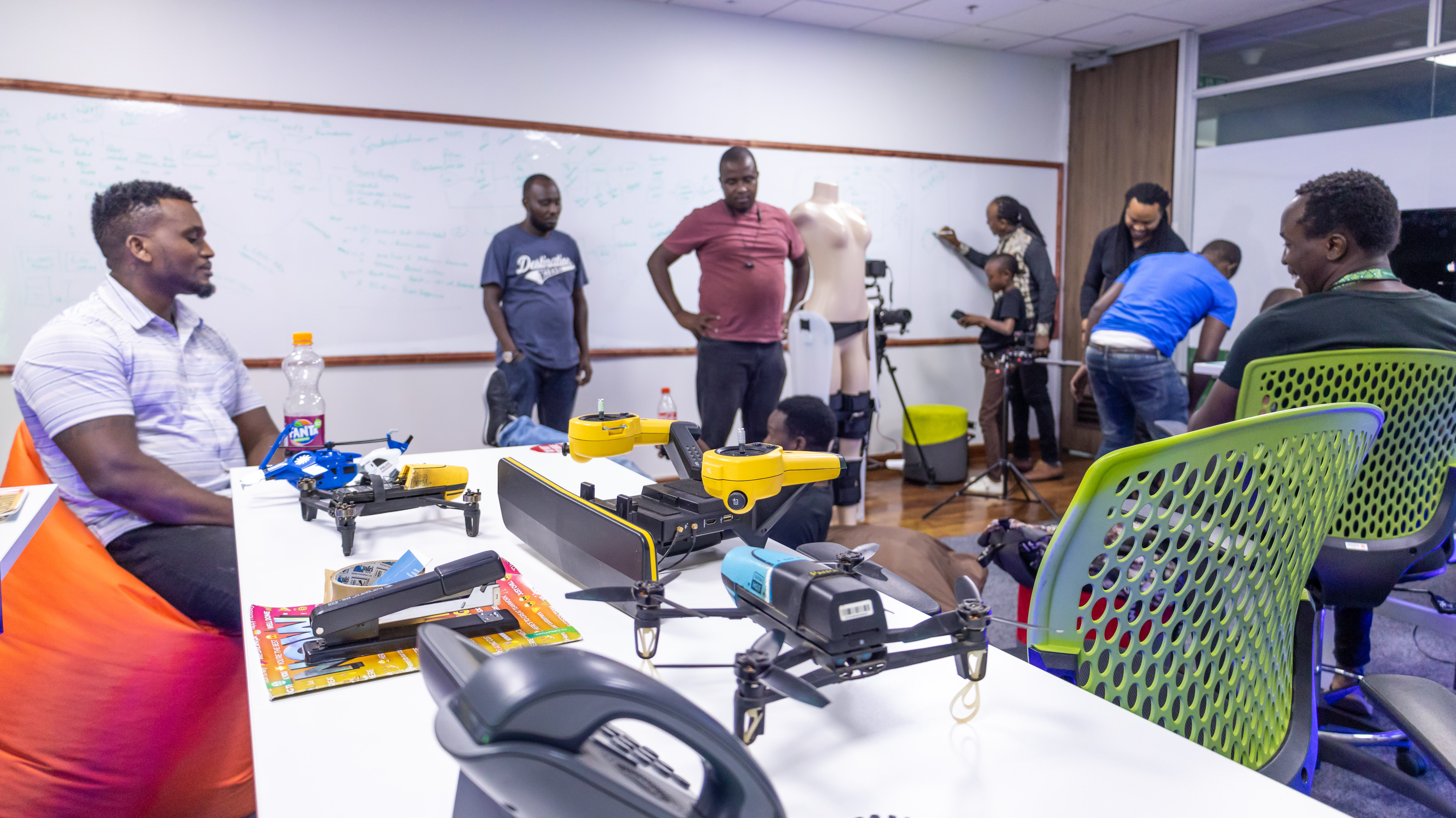 Drones and equipment on a table while cast and crew prepare in the background